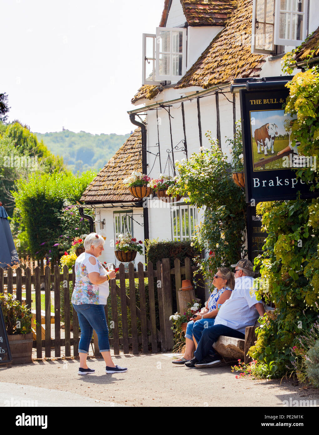 Les hommes et les femmes assis à parler et à boire à l'extérieur de la bulle et Butcher pub dans le Buckinghamshire village de Turville pour meurtres Midsomer Banque D'Images