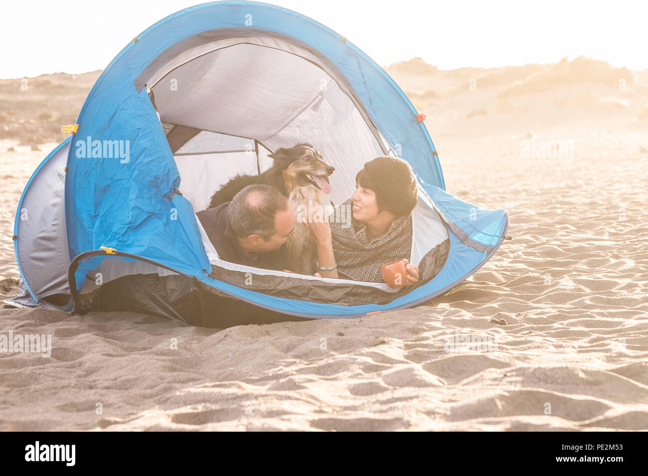 Couple dans une activité de loisirs camping libre de s'amuser à l'intérieur petite maison à la plage. Chien border collie derrière eux avec l'amour et l'amitié pour toujours Banque D'Images