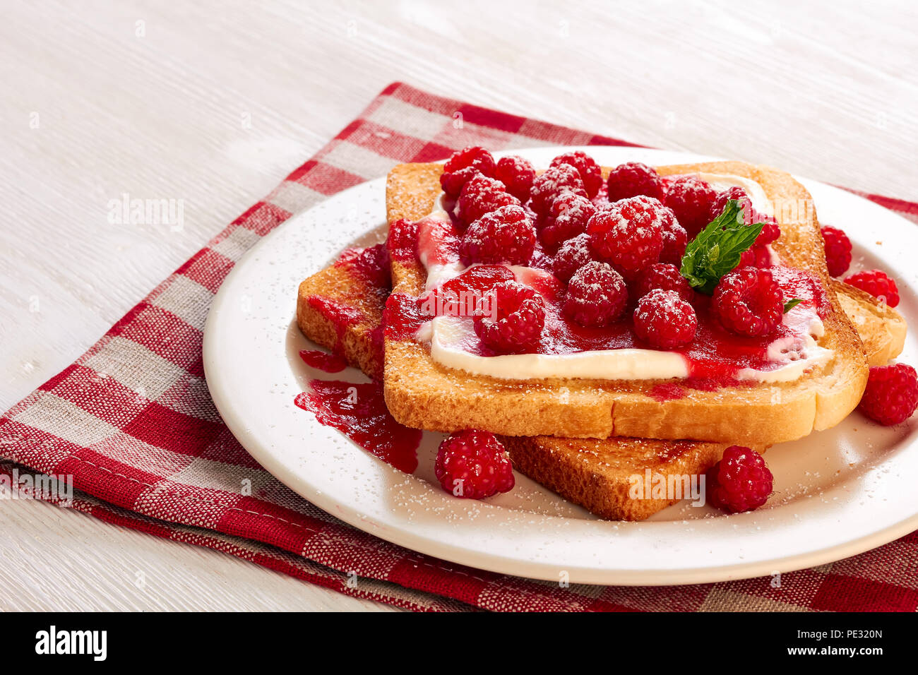 Toast avec du fromage blanc et framboises sur serviette textile Banque D'Images