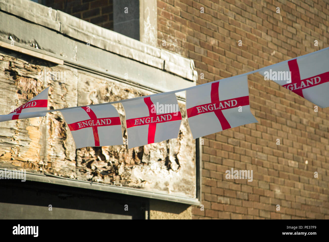 Une chaîne de l'Angleterre en plastique avec des drapeaux de la détérioration d'une boutique de signe derrière Banque D'Images