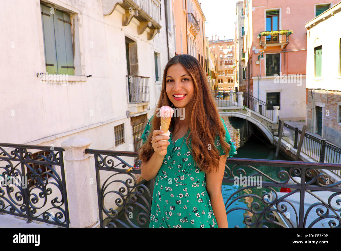 Jolie jeune femme en robe verte avec de la crème glacée dans ses vacances à Venise, Italie Banque D'Images