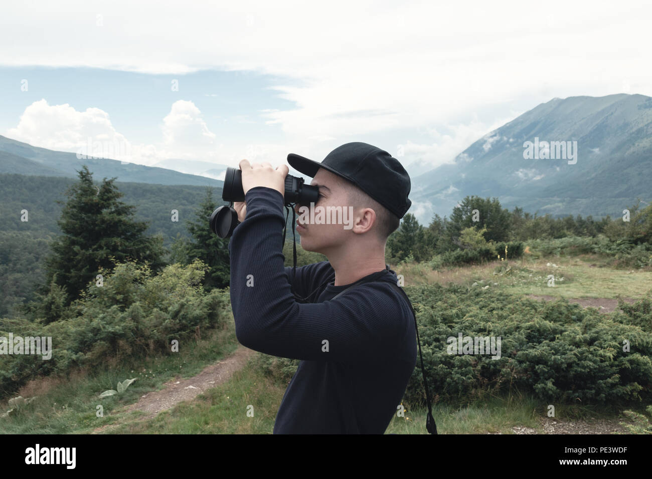 Randonneur regardant à travers des jumelles en face de collines et de montagnes. Prevalla, Prizren, Kosovo Banque D'Images