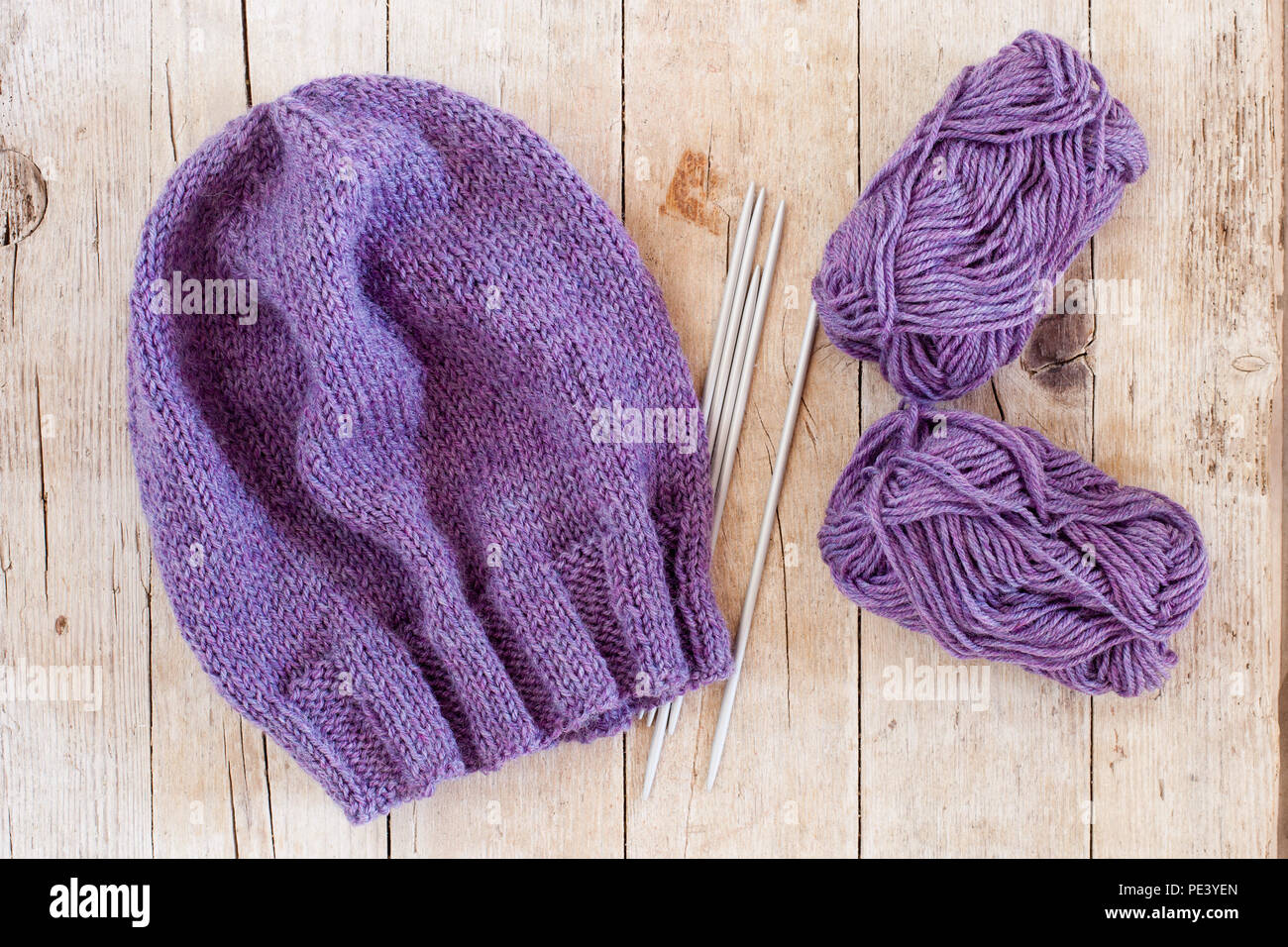 Chapeau violet laine, aiguilles à tricoter et la laine sur fond de bois Banque D'Images