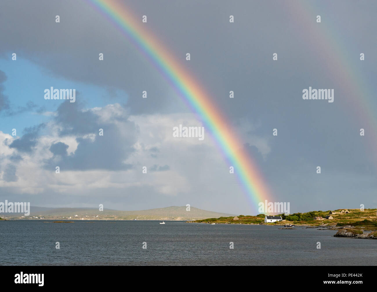 Arc en ciel et blanc cottage by the sea sur la côte du Connemara à l'ouest de l'Irlande Banque D'Images