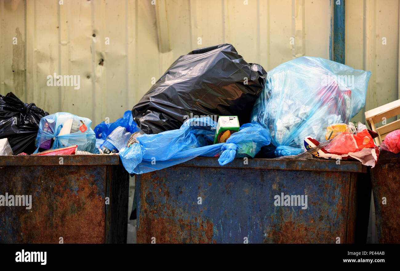 Metal urbain bleu poubelles plein de déchets ménagers les ordures ménagères et les sacs de plastique dans un sale état crasseux Banque D'Images