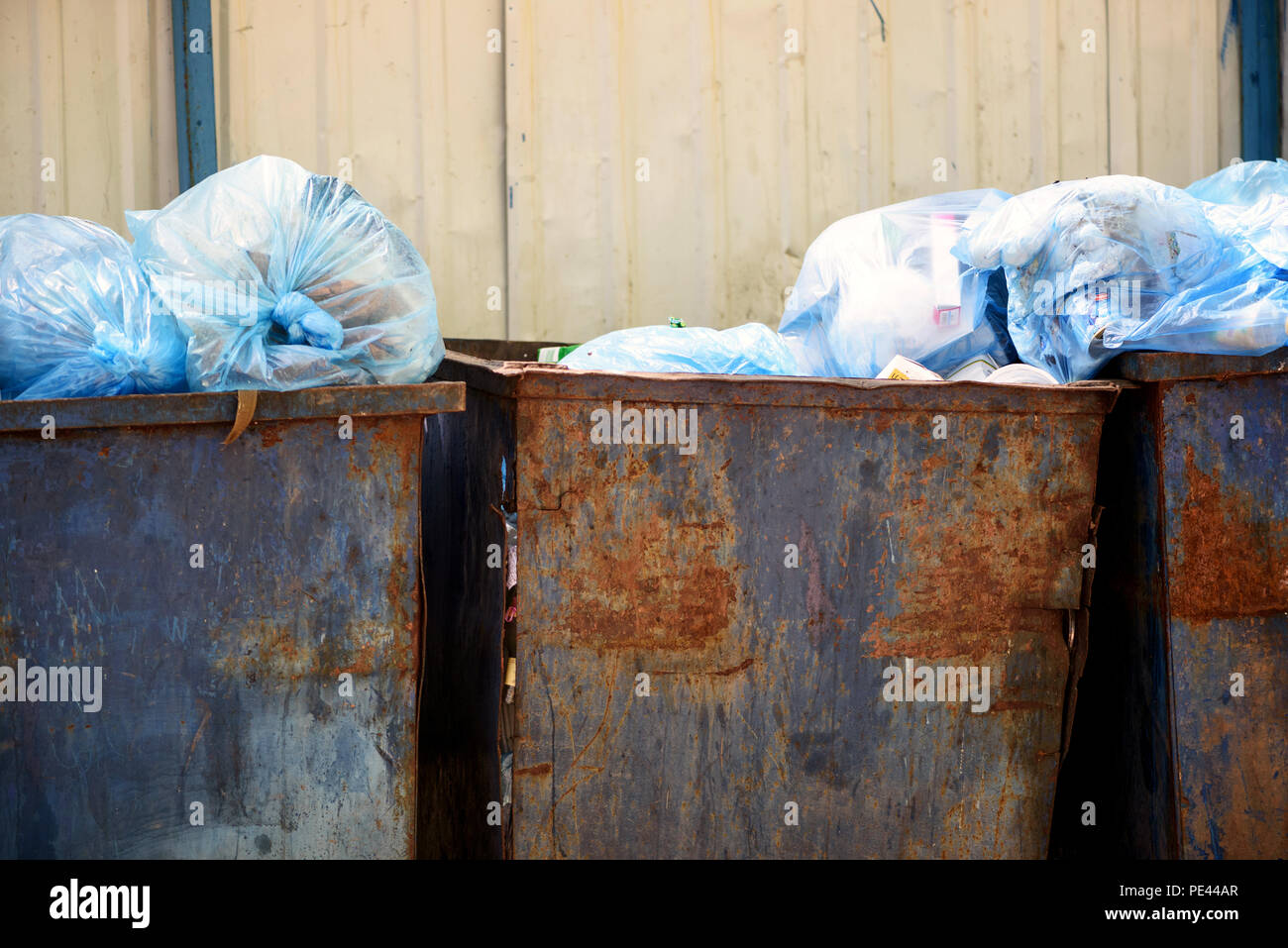 Metal urbain bleu poubelles plein de déchets ménagers les ordures ménagères et les sacs de plastique dans un sale état crasseux Banque D'Images