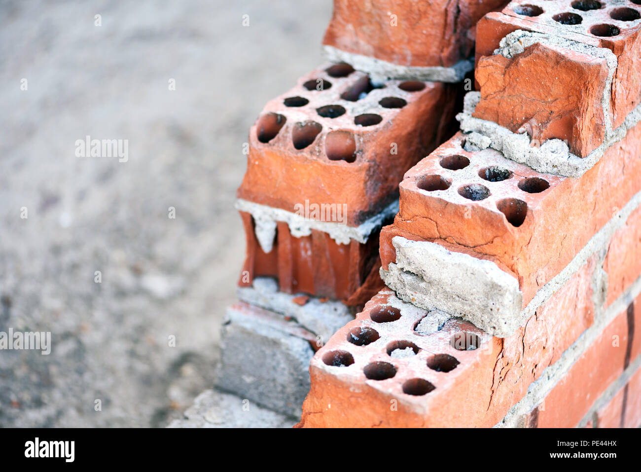 Les construisant briques rouges formant un mur en cours de construction au mortier de ciment visible Banque D'Images