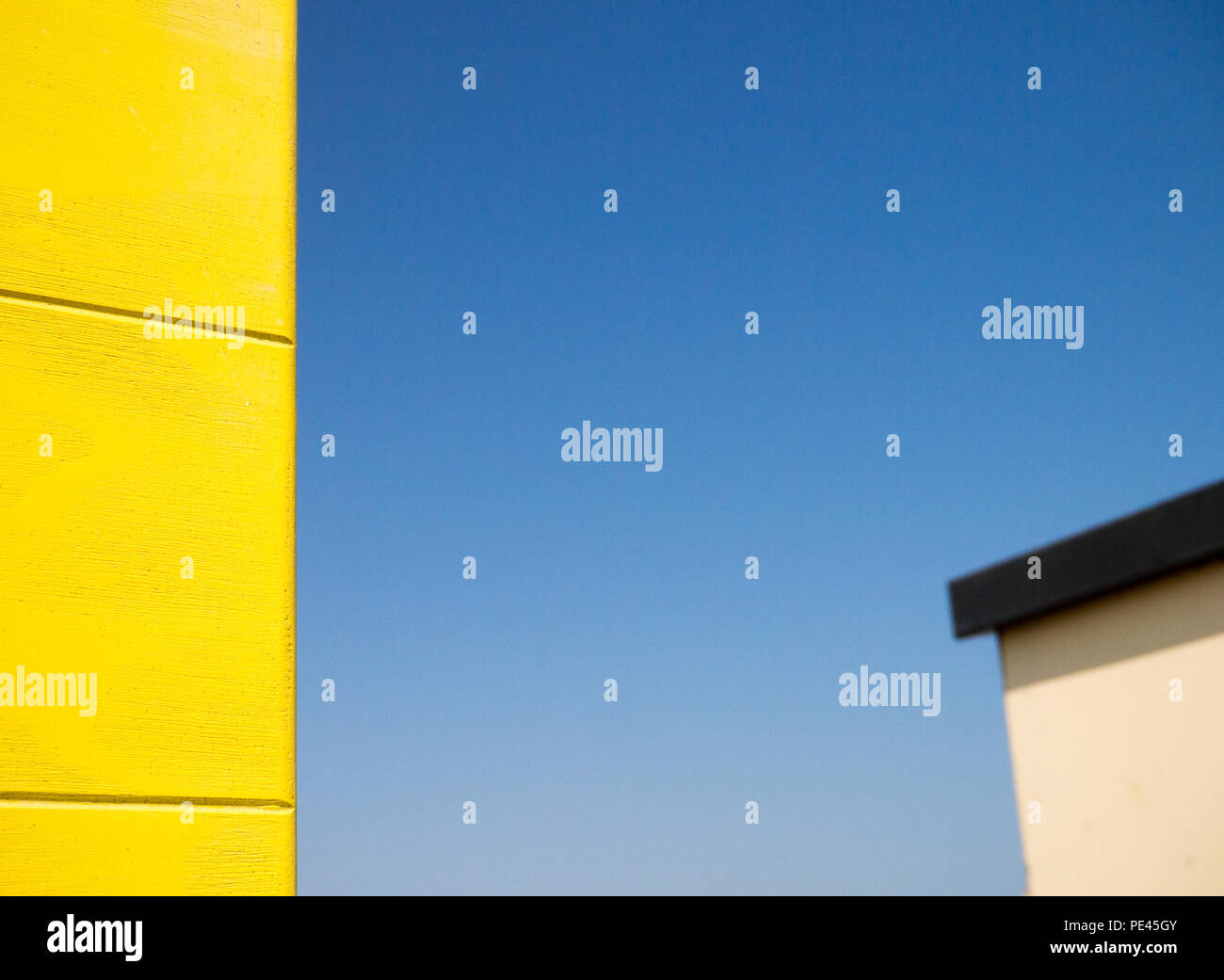 De couleur les bords de deux cabines de plage, une jaune et une couleur crème, contre un ciel bleu clair Banque D'Images