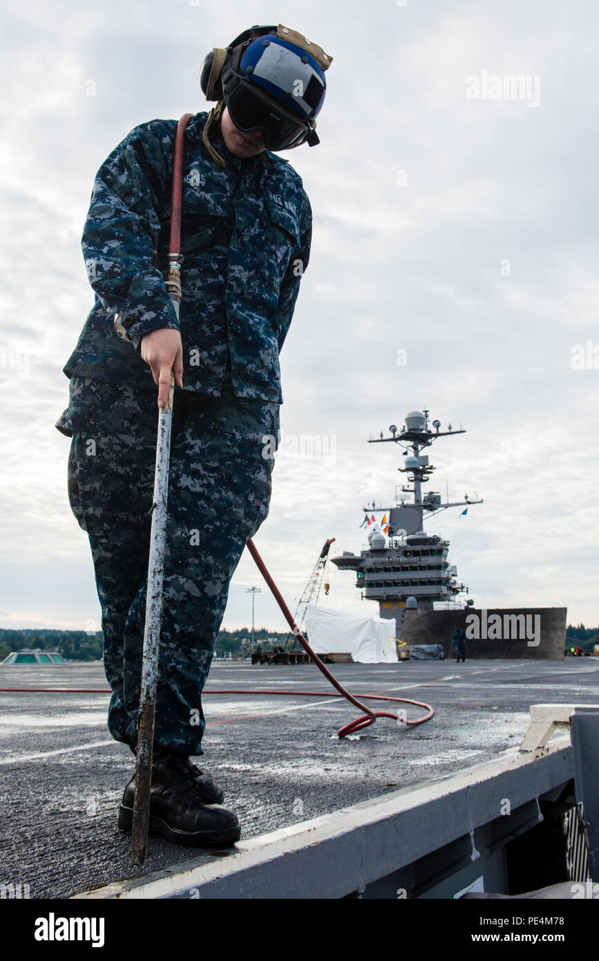 150918-N-DA737-014 Bremerton, dans l'État (sept. 18, 2015) - Aviation maître de Manœuvre (manutention) Airman Ashley Sims, de Rockport, Maine, utilise un tuyau d'air pour retirer l'eau et la poussière de l'USS JOHN C. STENNIS (CVN 74) envol scupper. L'équipage de Stennis est en ce moment à port la formation de futurs déploiements. (U.S. Photo par marine Spécialiste de la communication de masse de la classe 3ème Jonathan Jiang / relâché) Banque D'Images