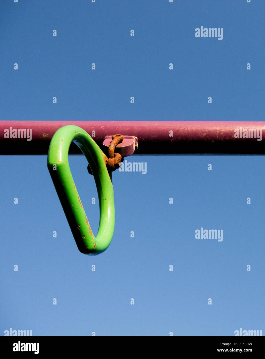 Image en couleur d'un green monkey bar poignée sur un poteau rouge dans une aire de jeux pour enfants, tourné à partir de ci-dessous contre un ciel bleu clair Banque D'Images