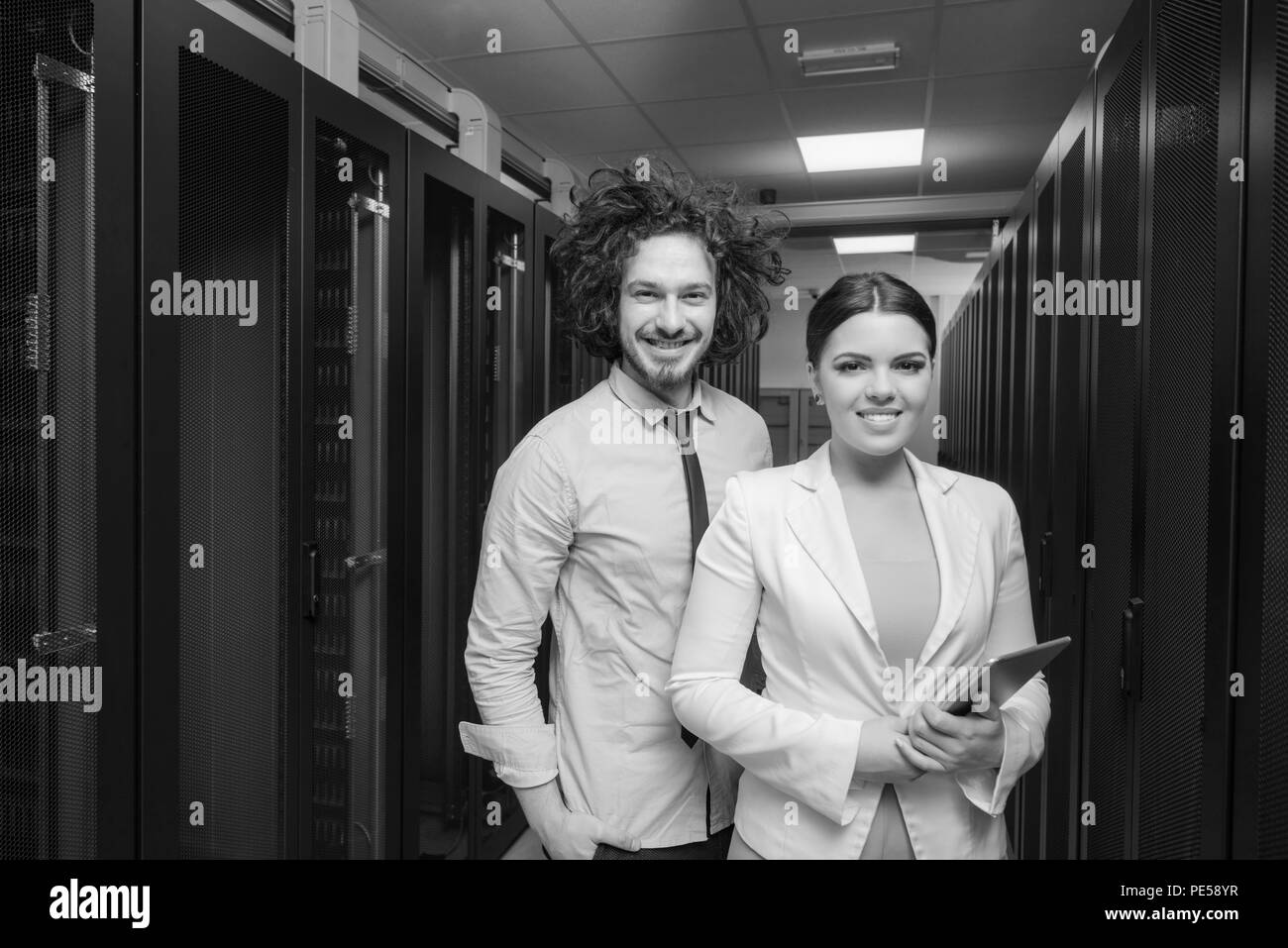 Jeune ingénieur en informatique serveur de centre de données de travail montrant prix à femme ingénieur en chef qui holding tablet computer Banque D'Images