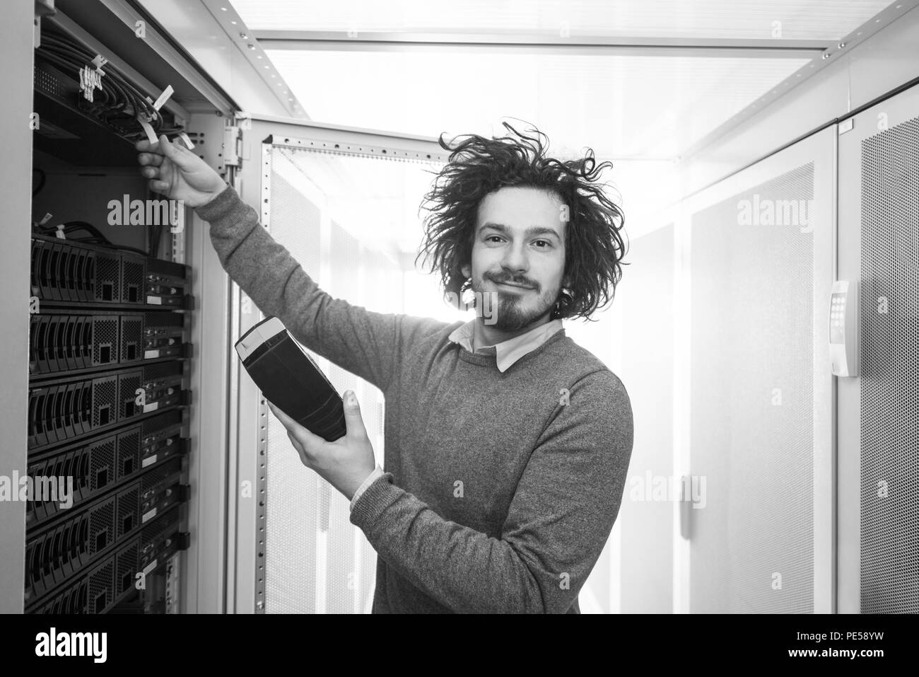 Jeune technicien en informatique à l'aide de l'analyseur de câble numérique sur le serveur en grand centre de données Banque D'Images