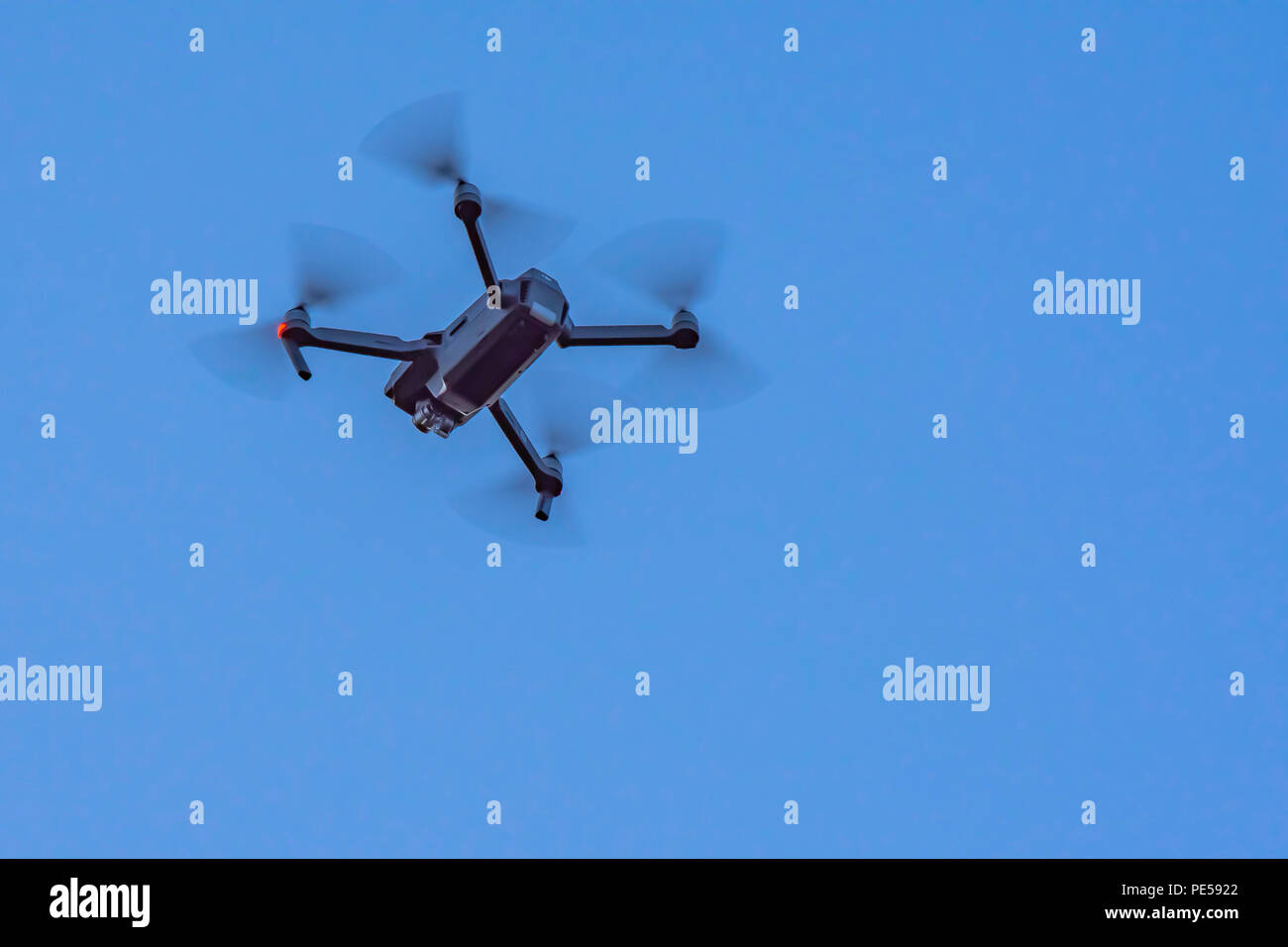 Drone caméra noir, avec le mouvement des hélices visibles et gyrophare sur  fond de ciel bleu Photo Stock - Alamy