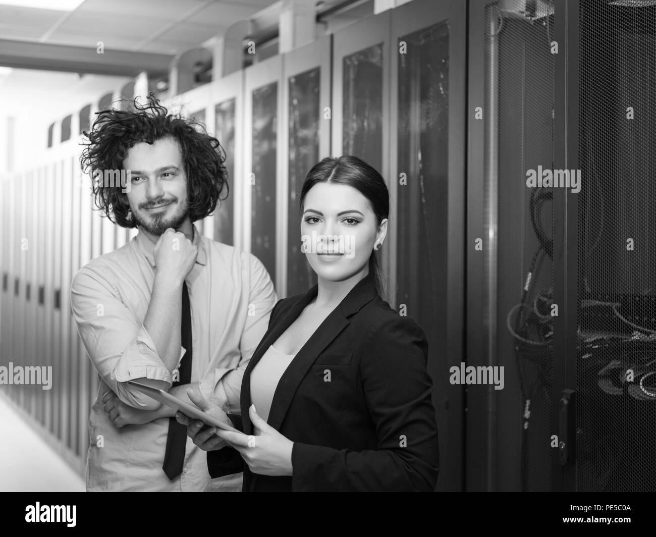 Jeune ingénieur en informatique serveur de centre de données de travail montrant prix à femme ingénieur en chef qui holding tablet computer Banque D'Images