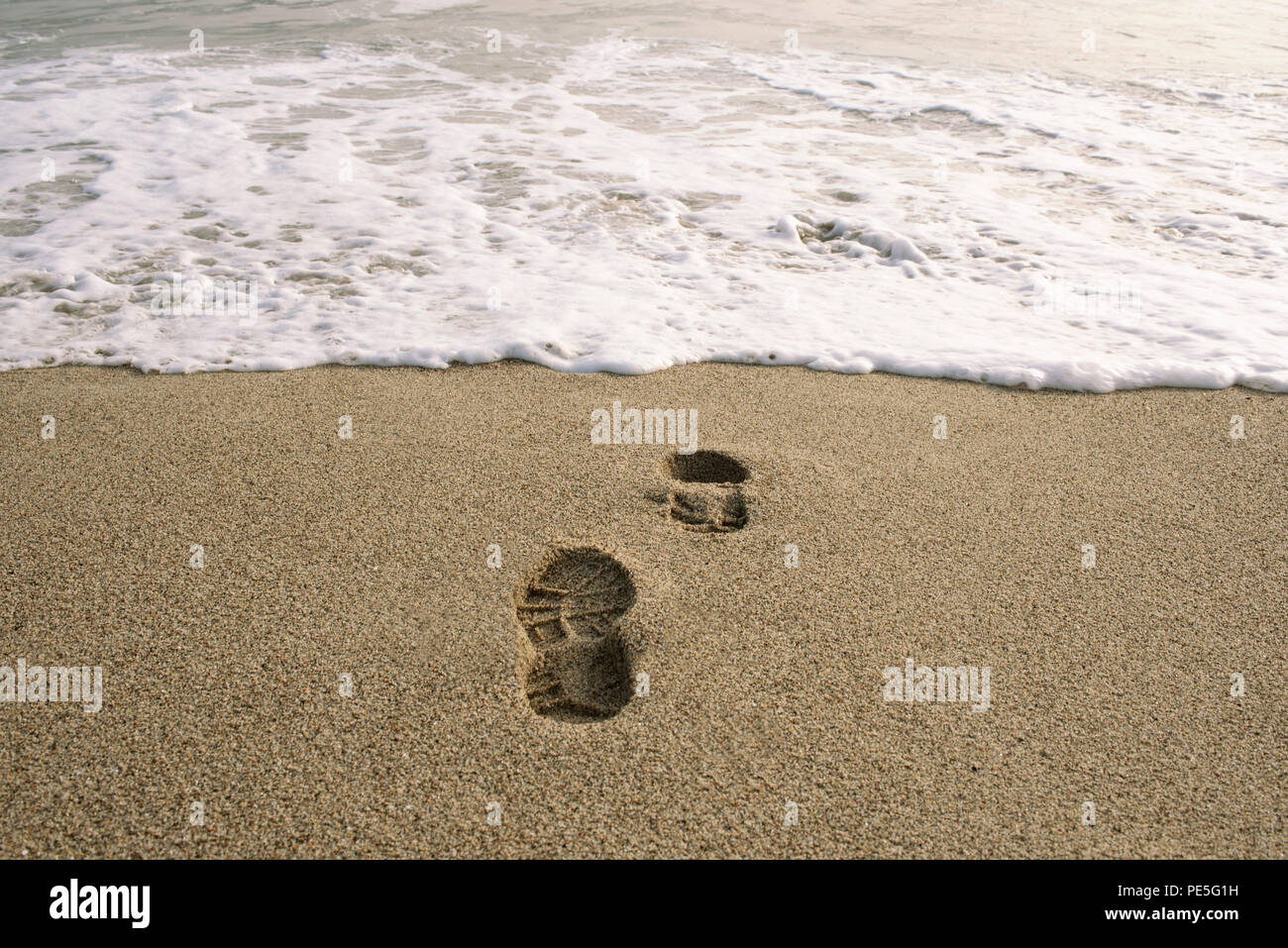 Avalée par la mer. Image conceptuelle d'empreintes de chaussures dans le sable. Punta Hermosa, le Pérou. Jul 2018 Banque D'Images