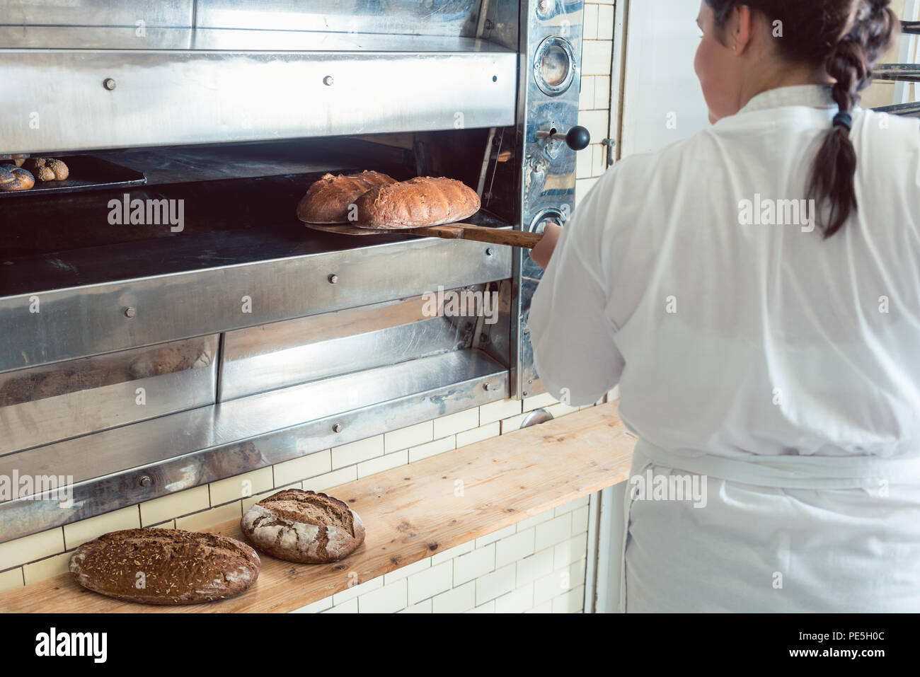 Baker obtenir du pain frais avec pelle hors du four Banque D'Images