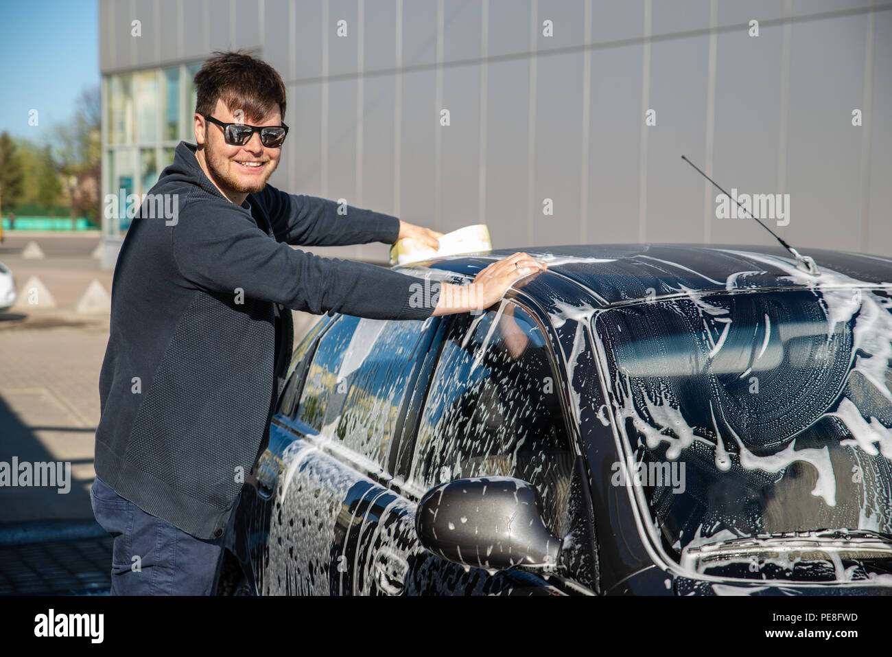 Jeune homme à lunettes de voiture à laver self service carwash Banque D'Images