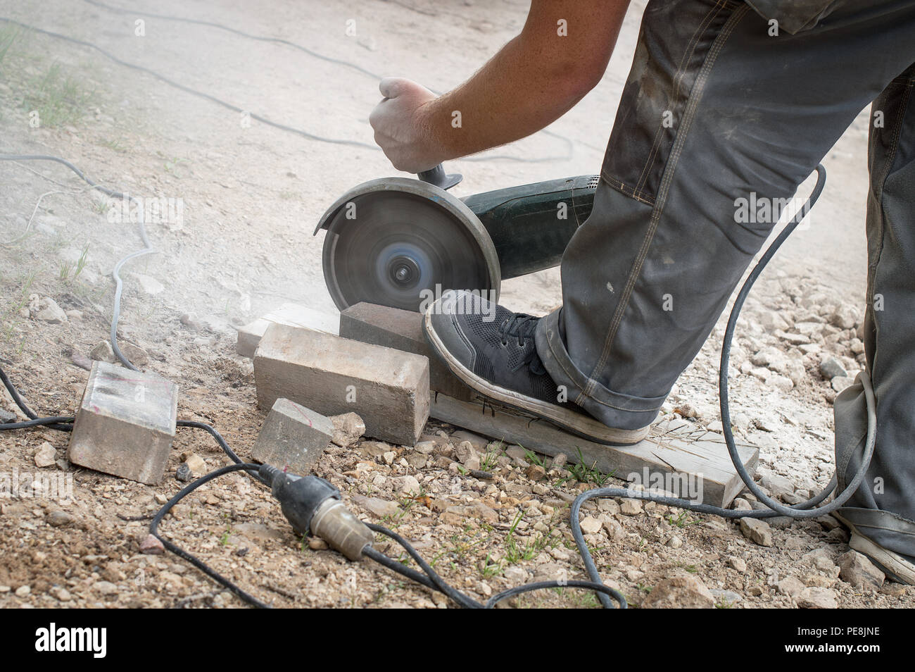 Travailleur avec coupe carreaux électrique vu de la chaussée en petits morceaux Banque D'Images