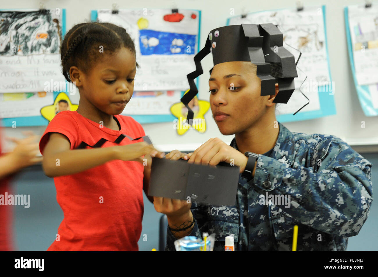 151030-N-RC734-100 SAN DIEGO (oct. 30, 2015) - 2e classe Mate du machiniste Kay Acy travaille sur un projet d'art et d'artisanat avec un étudiant au cours d'un événement de relations communautaires entre le quai de transport amphibie USS San Diego (LPD 22) et Tierrasanta école élémentaire. Les marins affectés à l'USS San Diego ont une relation de longue date avec l'école et régulièrement des partenariats avec des classes pour différents événements. San Diego est actuellement amarré à côté de la jetée de San Diego BAE chantier pour une longue période de maintenance. (U.S. Photo par marine Spécialiste de la communication de masse Joseph M. 1ère classe Buliavac/libérés) Banque D'Images