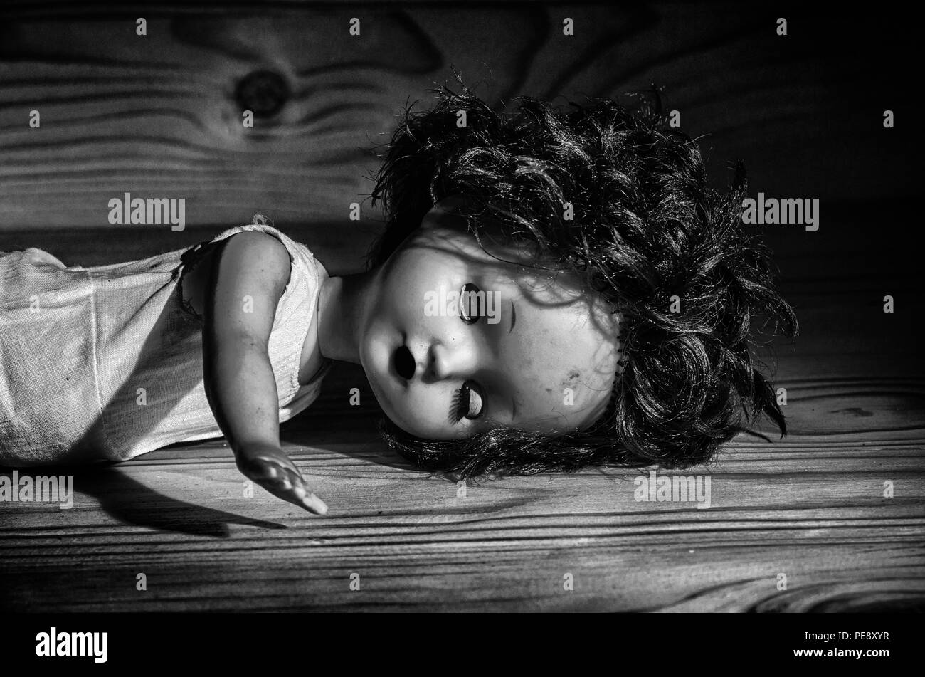 Une vieille poupée cassée sur une table en bois en noir et blanc. Banque D'Images