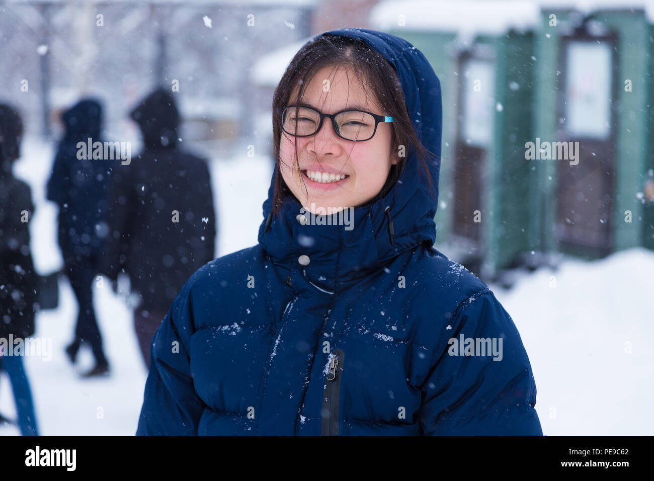 Happy Young Asian female adolescent dans un épais manteau d'hiver bleu profitez d'être à l'extérieur pendant l'hiver la neige, bon pour en toute sécurité avec une assurance vie ou attitude positive co Banque D'Images