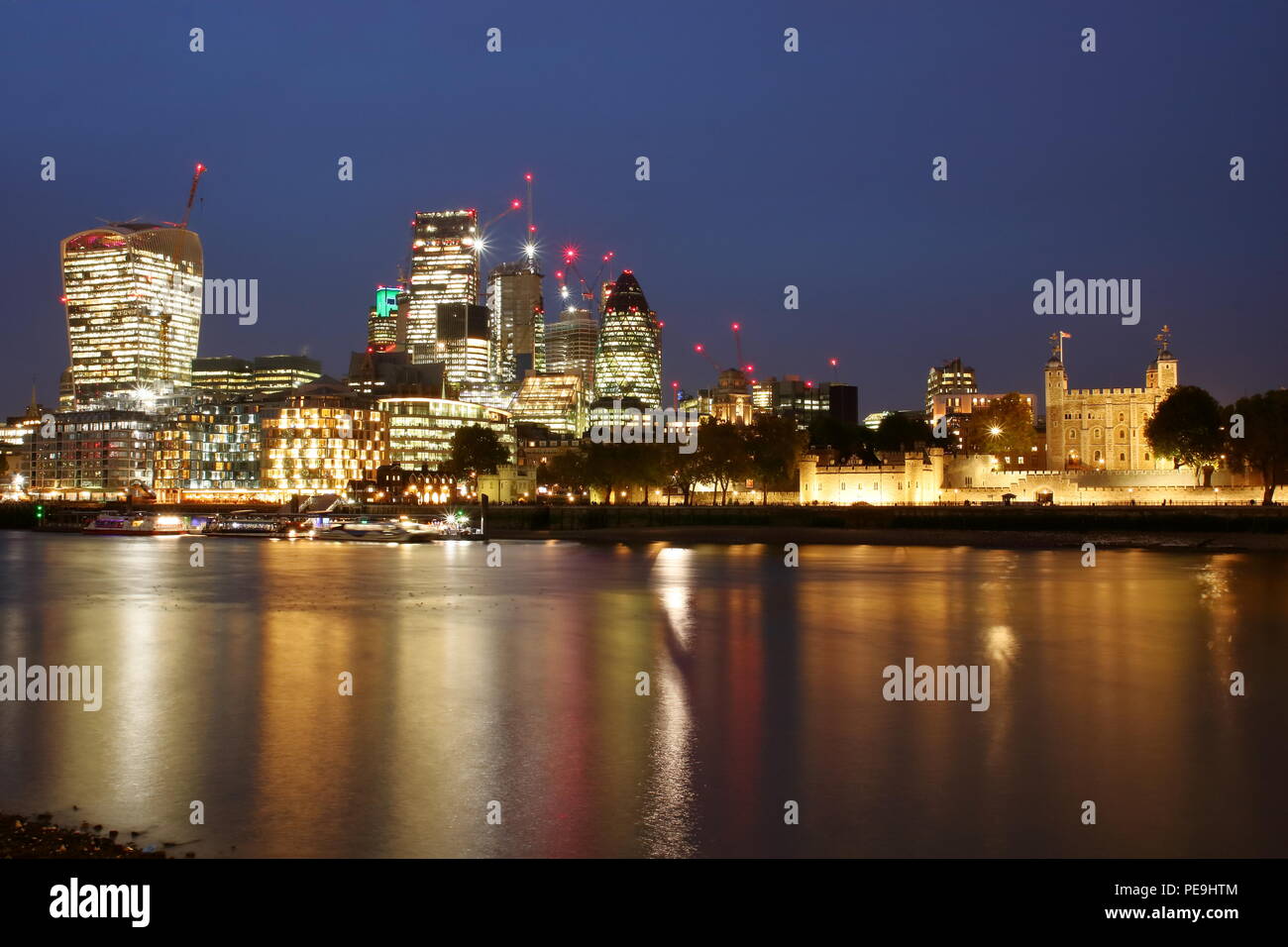 Avec la ville de Londres Thames River par nuit, réflexions sur l'eau, illuminé des gratte-ciel, l'architecture moderne, la Tour de Londres, long exposure Banque D'Images