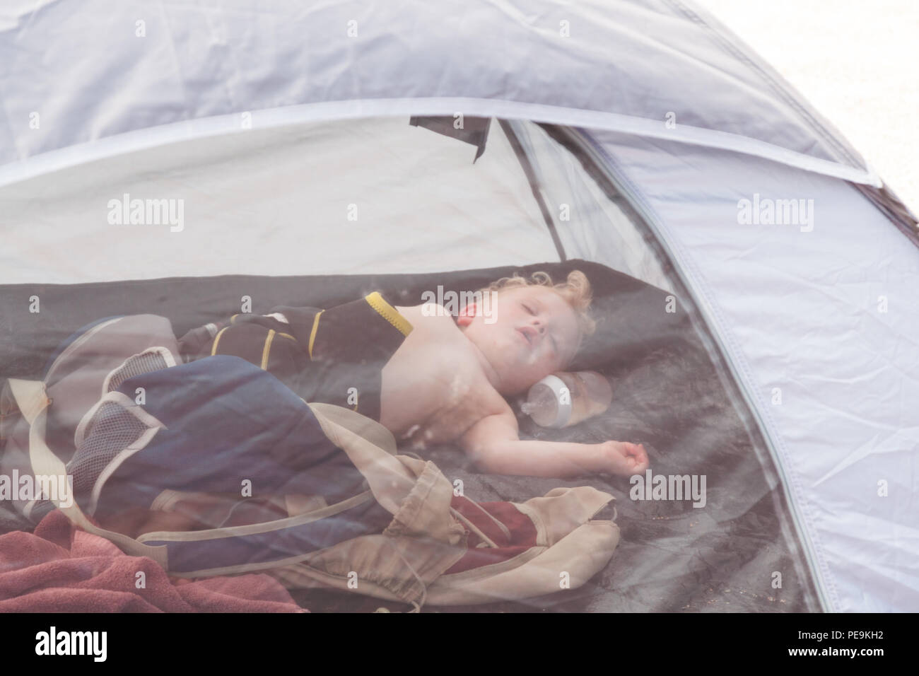 Deux ans garçon bébé dormir dans un abri de plage, Devon, Angleterre, Royaume-Uni. Banque D'Images