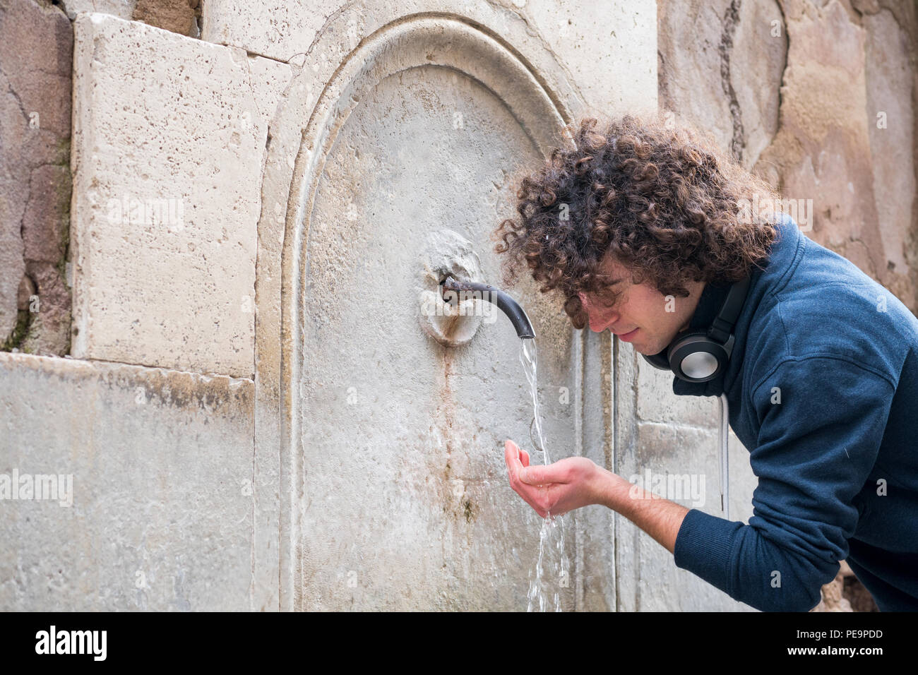 Jeune homme boit de l'eau d'une fontaine Banque D'Images