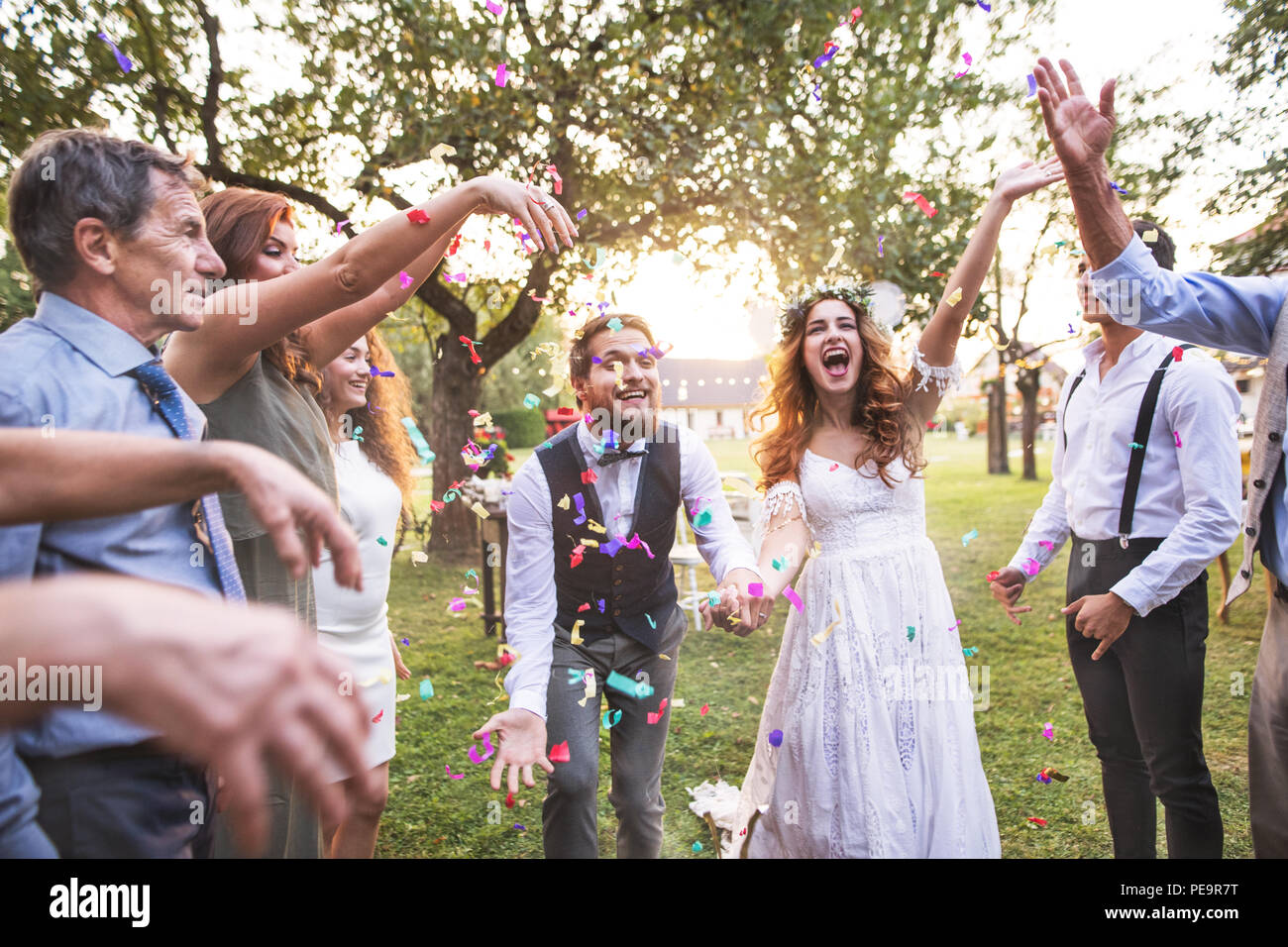 Mariée, marié et vous jeter des confettis à réception de mariage à l'extérieur. Banque D'Images