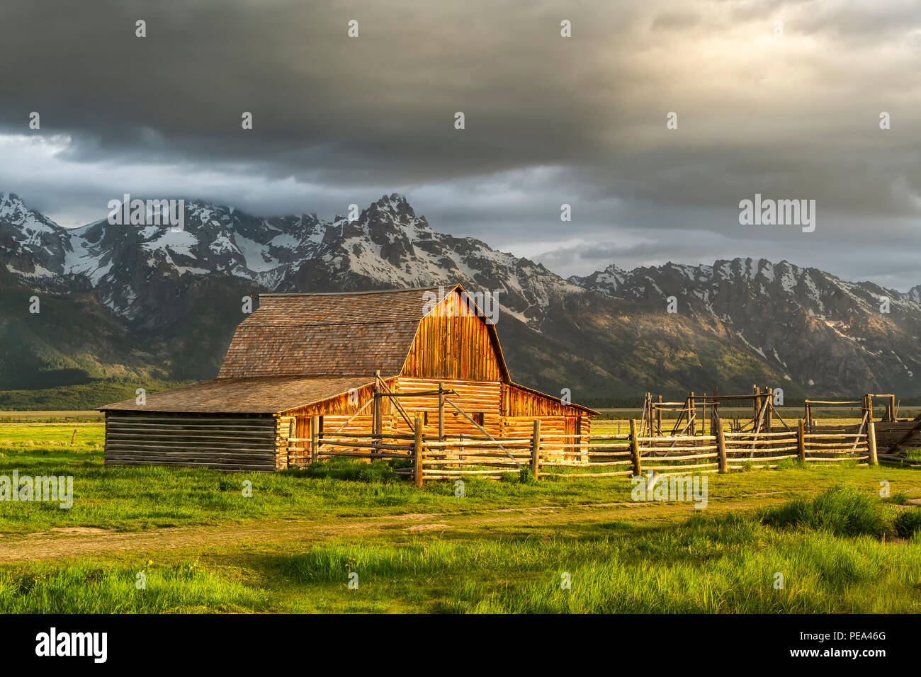 Le Moulton Grange dans la lumière du matin chaud avec de gros nuages sur le Grand Teton Mountain Range dans l'arrière-plan Banque D'Images