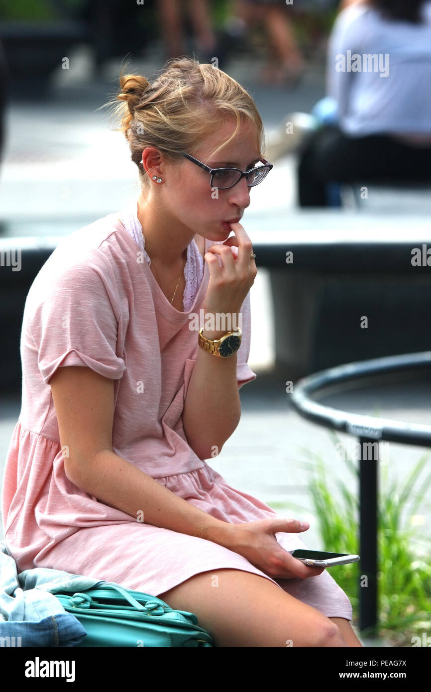 NEW YORK, NY - 05 SEPTEMBRE : Jeune femme blanche vérifie son téléphone tout en restant assis à Washington Square Park, à Manhattan, le 5 septembre 2016 à New York, U Banque D'Images