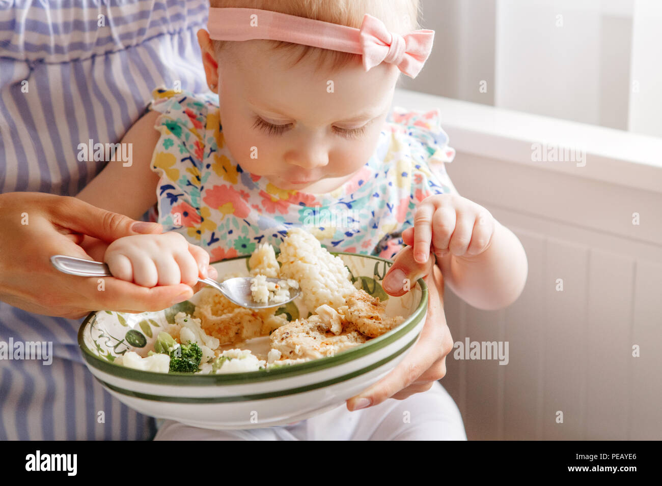 Closeup portrait of young woman mère nourrit sa fille fille avec légumes Brocoli Chou-fleur. Aliments biologiques sains pour les enfants. Natures mortes candide Banque D'Images