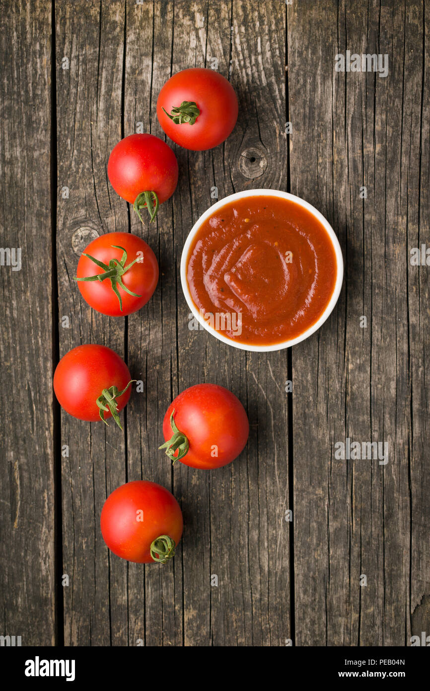 La tomate et le ketchup sur la vieille table en bois. Banque D'Images