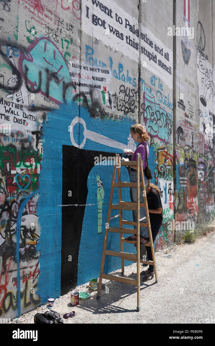 Graffiti artistes travaillant sur le mur de séparation à Bethléem. À partir d'une série de photos de voyage prises à Jérusalem et dans les environs. Date de la photo : Wedne Banque D'Images