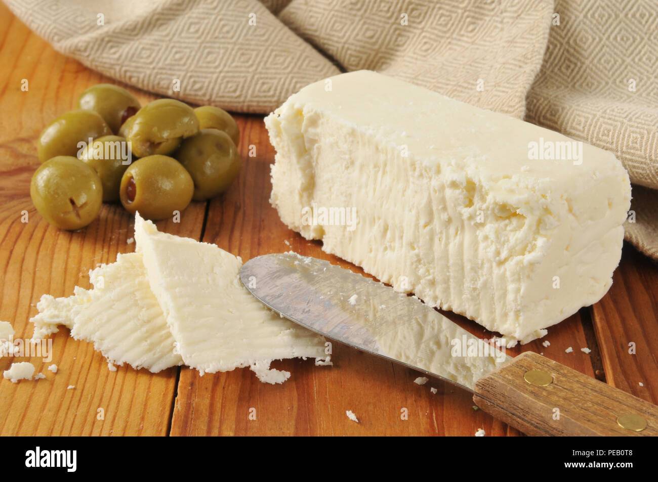 Un bloc de fromage féta olives vertes farcies avec rustique sur une planche à découper. Image alimentation stock photos. Banque D'Images