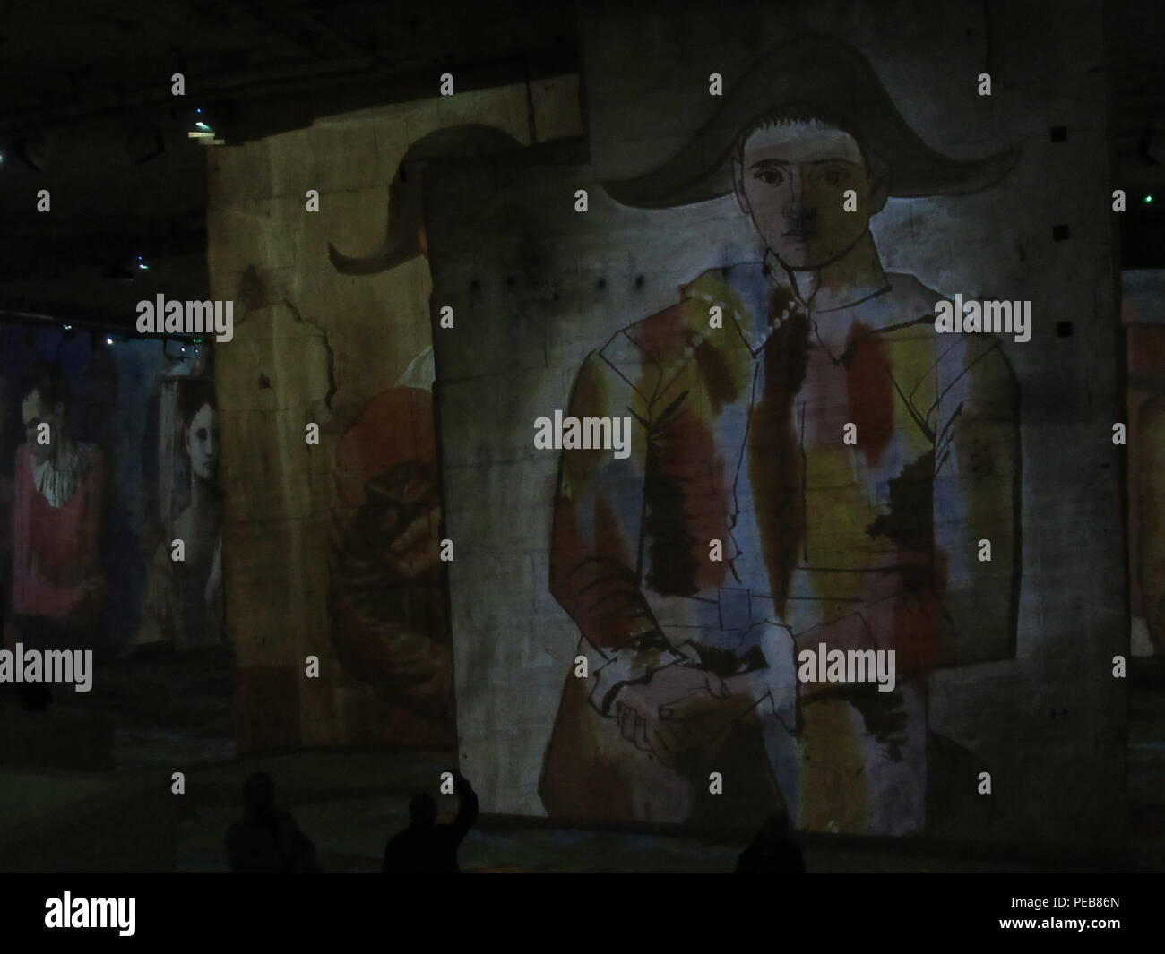 07 août 2018, en France, à Les Baux-de-Provence : une grande projection de l'œuvre 'Arlequins avec plié mains' de Pablo Picasso est projeté contre un mur à la présentation multimédia 'Picasso und die Meister, 'Der stumme' dans les carrières de carrières de lumières, à environ 70 kilomètres d'Aix-en-Provence. Les chefs d'œuvre de grands artistes sont projetés sur l'jusqu'à 16 mètres de haut, colonnes et murs sur une surface d'environ 7000 mètres carrés. Photo : Sabine Glaubitz/dpa Banque D'Images