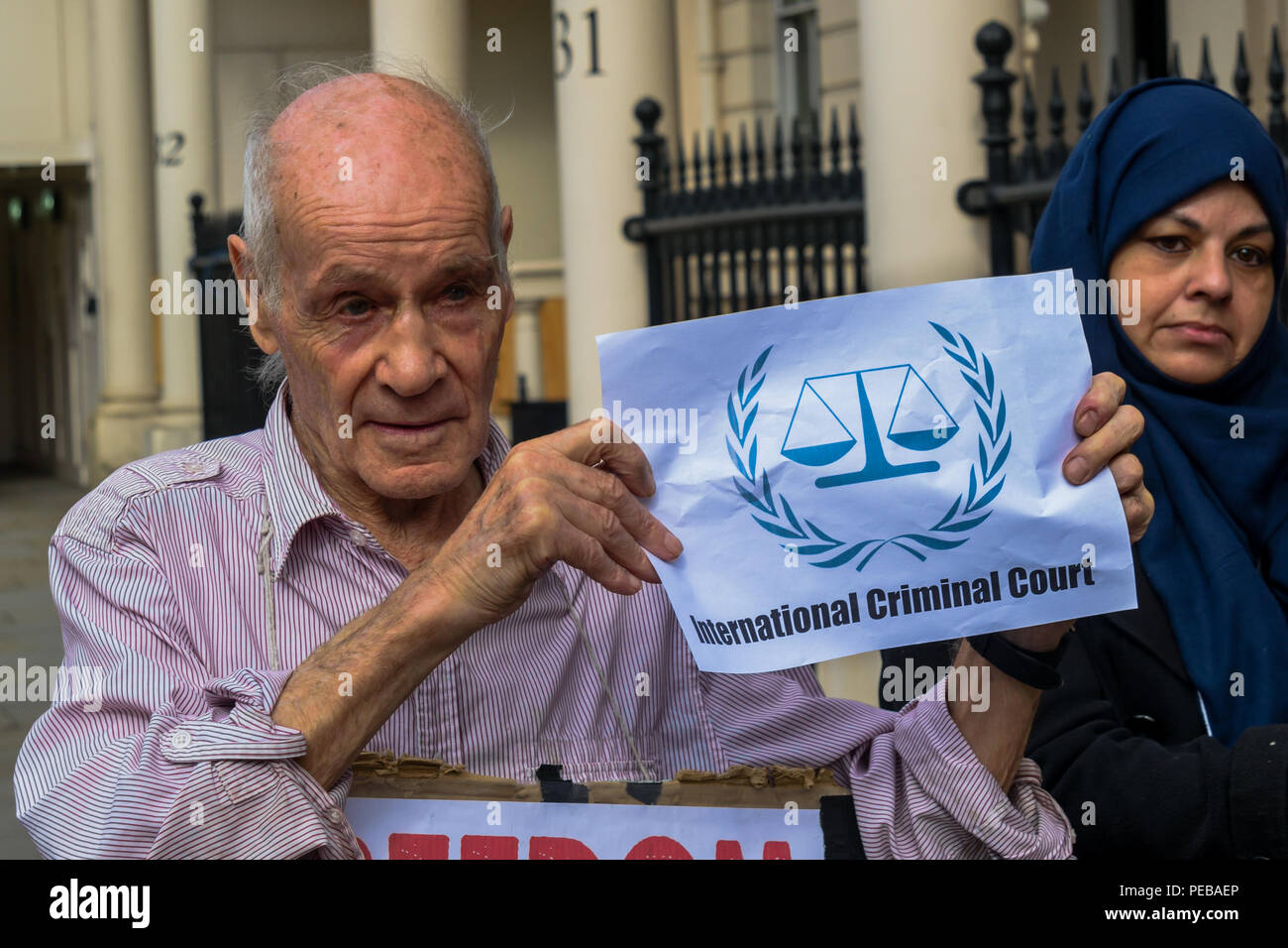 Août 13, 2018 - Londres, Royaume-Uni. 13 août 2018. La courte pièce de théâtre de rue se termine avec les manifestants dans les masques pour "Fournisseur d'armes', Mai Theresa Boucher de Bahreïn Hamid Khalifa' et 'Petit Stooge Fawaz Khalifa' dans les chaînes et prises à la Cour pénale internationale pour leurs crimes contre le peuple de Bahreïn. Les manifestants ont défié la police qui leur a dit qu'ils ne peuvent pas protester sur la chaussée à l'extérieur de l'ambassade de Bahreïn à l'appui de gréviste de la faim Ali Mushaima qui a été à l'extérieur de l'ambassade de Bahreïn dans Belgrave Square depuis le 1er août, pour lui demander son père âgé de 70 ans de priso Banque D'Images