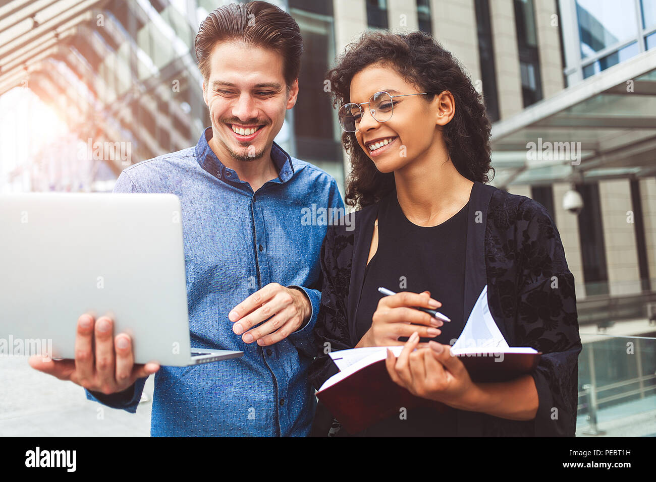 Deux collègues sont souriants discutent dans la rue pendant la pause déjeuner près de l'édifice en arrière-plan. Banque D'Images