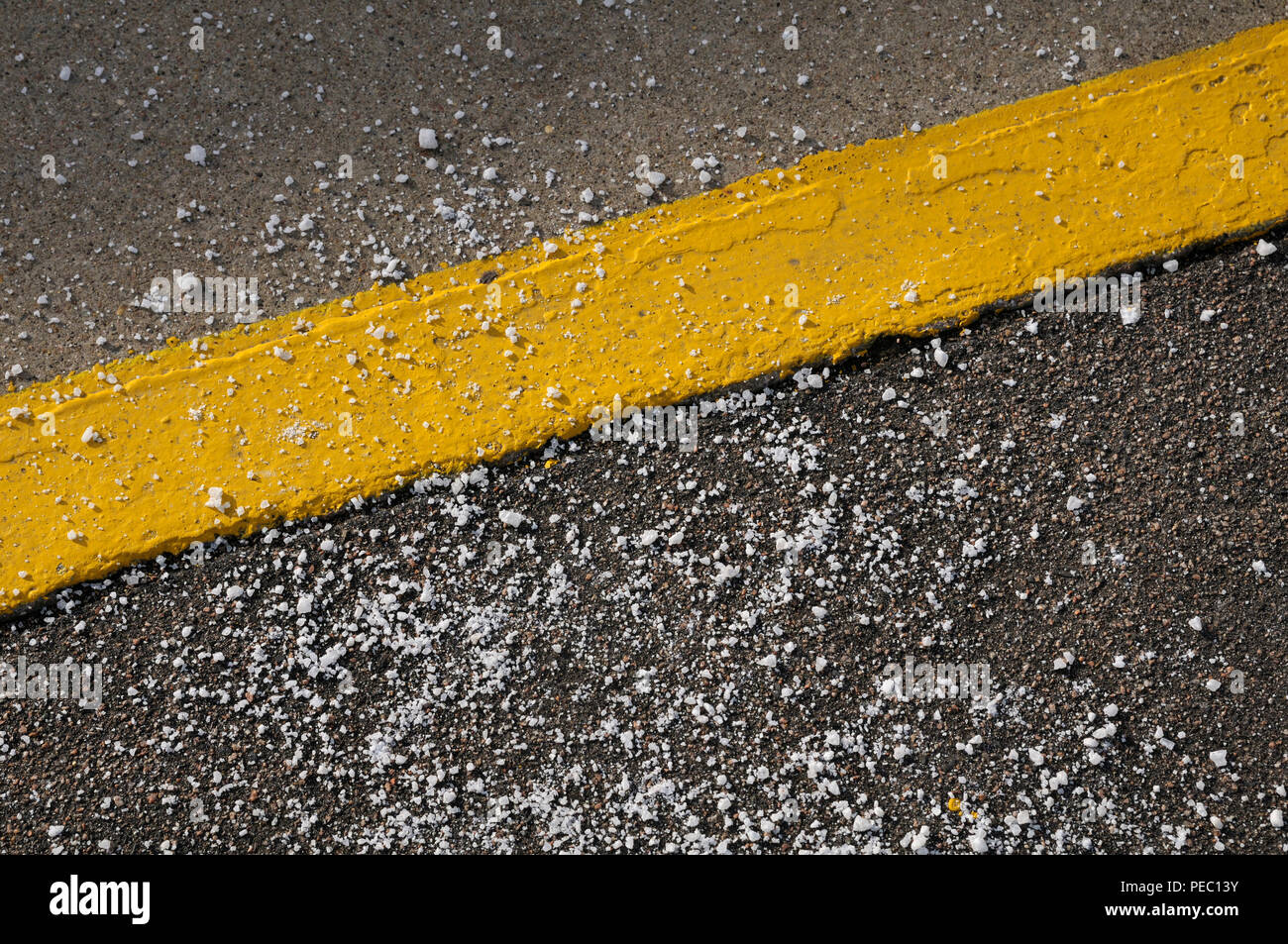 Grain de sel routier / rock / sel chlorure de sodium éparpillés autour d'une ligne jaune peinte Banque D'Images