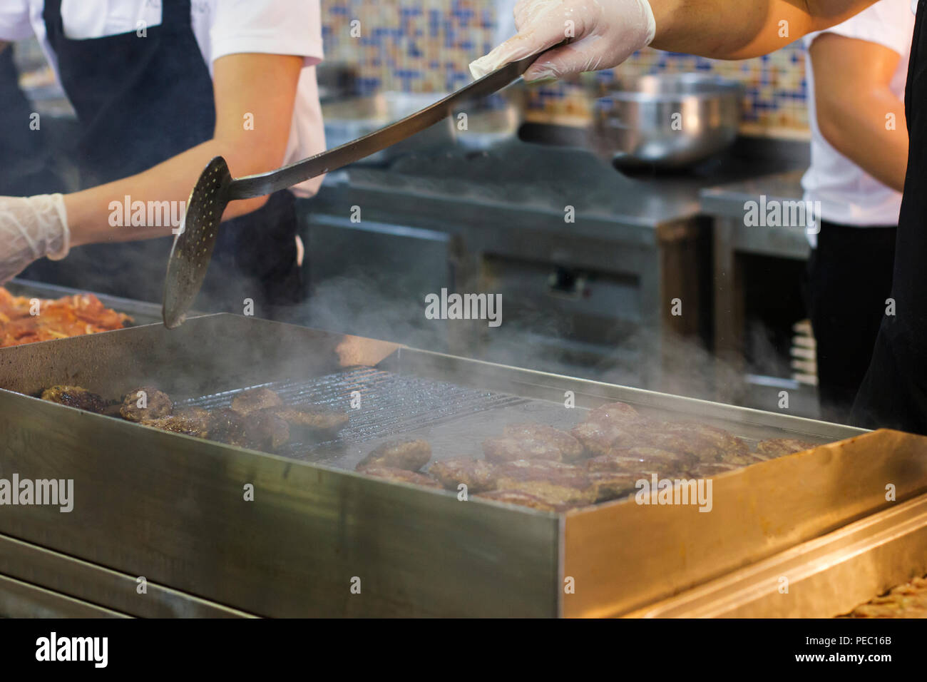 L'homme de viande et de frites escalopes burger sur une grille de cuisson Banque D'Images