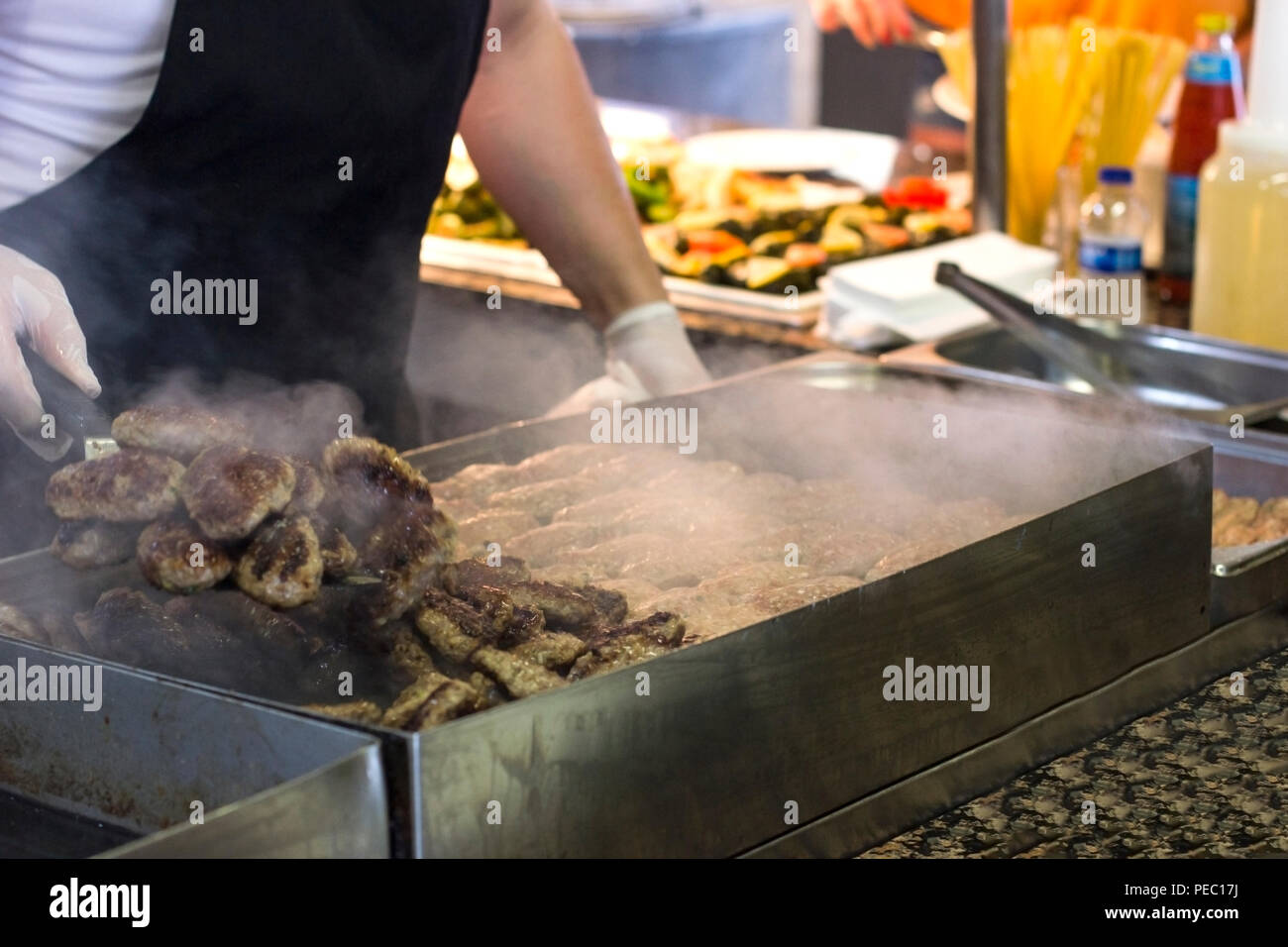 L'homme de viande et de frites escalopes burger sur une grille de cuisson Banque D'Images