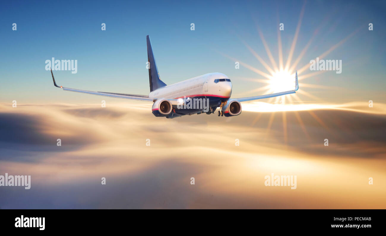 Avion de passagers. Paysage avec Big White est un avion volant dans le ciel rouge sur les nuages et la mer au coucher de soleil colorés. Avion de passagers est landi Banque D'Images