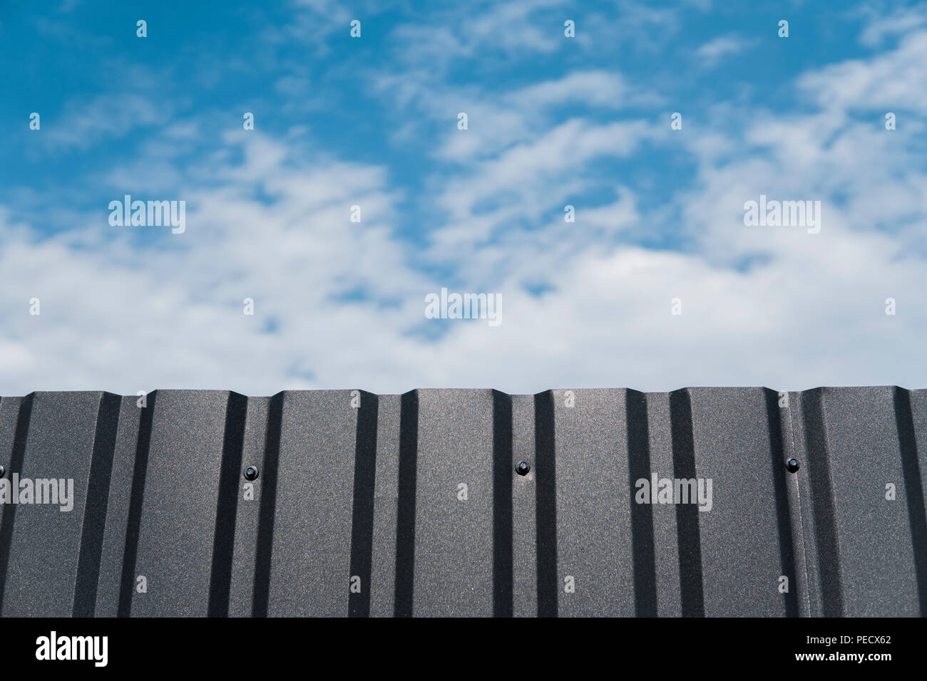 Plaque de métal brun contre blue cloudy sky. D'évitement. Surface sans couture d'acier galvanisé. Bâtiment industriel mur fait de feuille de métal ondulé, texture de fond photo Banque D'Images