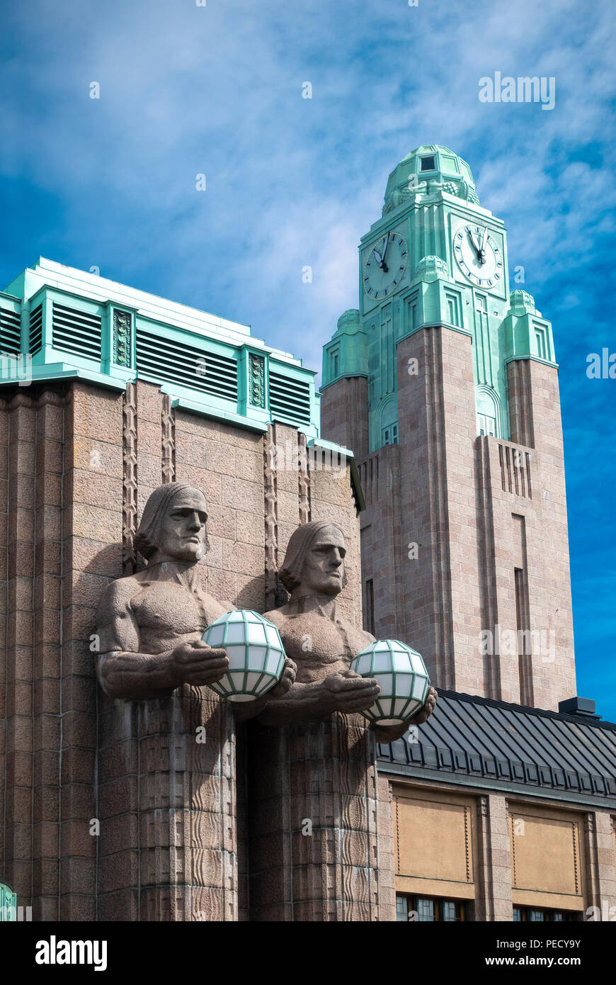 La gare centrale de Helsinki avec deux hommes de pierre statues holding lampes et la gare la tour de l'horloge. Banque D'Images