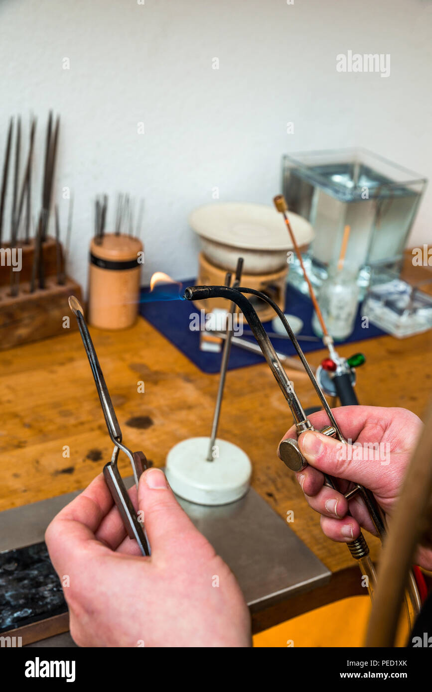 Goldsmith travaillant avec un chalumeau flamme sur un morceau de bijoux au lieu de travail Banque D'Images