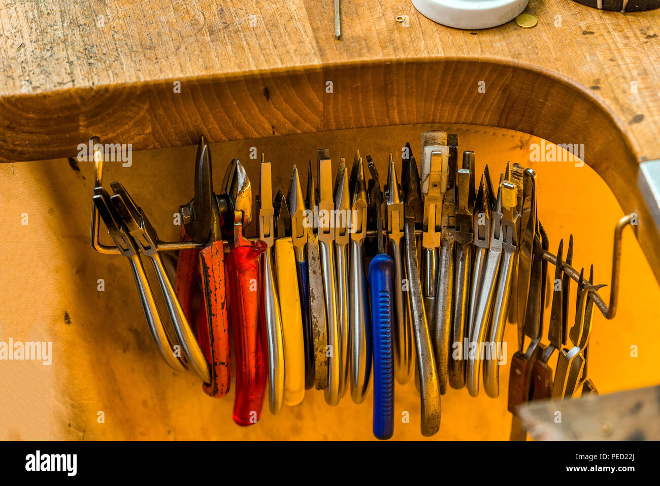 L'équipement et des outils d'un orfèvre avec pinces et pinces et tenailles suspendue à un bureau de travail en bois à l'intérieur d'un atelier Banque D'Images