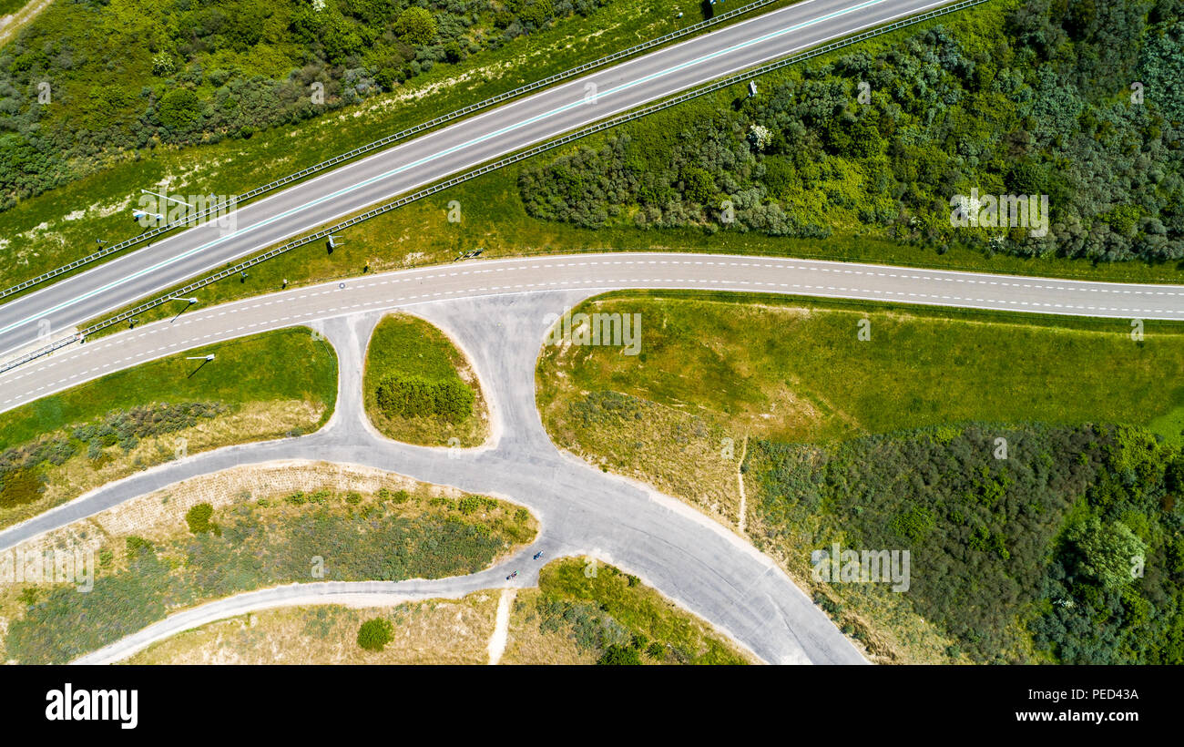 Panneaux route et piste cyclable entouré d'herbe verte et des arbres pris de dessus avec drone Banque D'Images