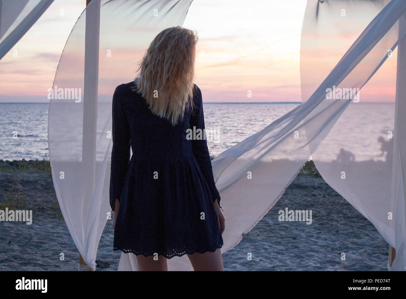 Belle fille ou femme silhouette sur fond coucher de soleil près de la mer ou l'océan en voile transparent Banque D'Images