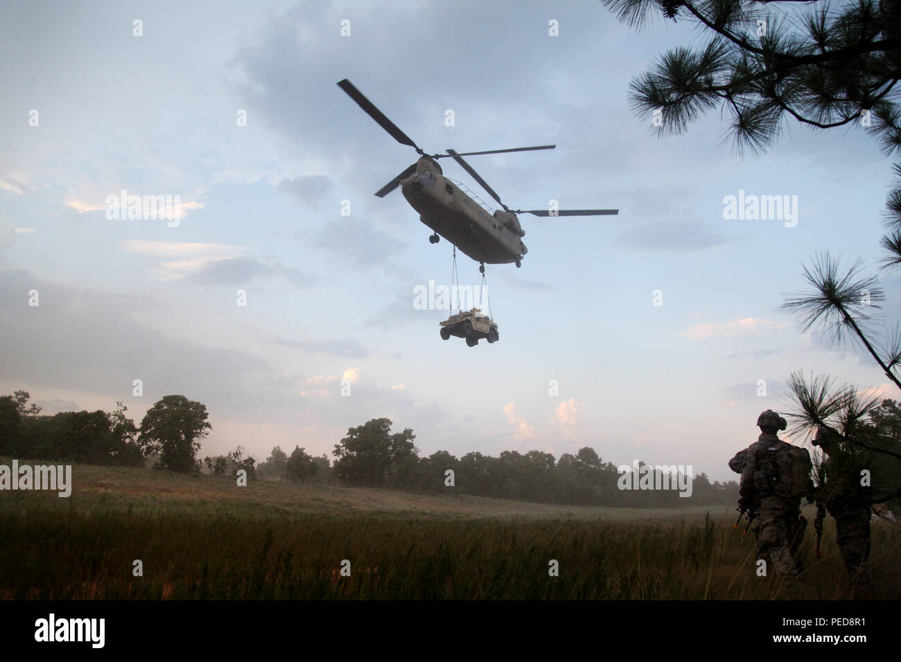 Des parachutistes du 1er bataillon du 508e régiment d'infanterie parachutiste observent un hélicoptère Boeing CH‑47 Chinook de la 82e brigade d'aviation de combat qui effectue un levage de charge à élingue d'un Humvee lors d'un entraînement d'assaut aérien conjoint à Fort Bragg, en Caroline du Nord. Les turboréacteurs jumelés Honeywell T55 et la conception du rotor tandem du CH‑47 offrent une capacité de levage lourd pour le transport d’équipement et de troupes dans les opérations d’assaut aérien et de charge tactique soutenant les unités aéroportées.  :ContentReference[oaicite :1]{index=1} Banque D'Images