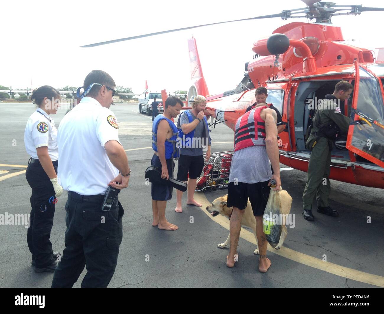 Les trois personne de l'équipage du Brandi Anne quitter un hélicoptère MH-65 Dolphin à l'équipage de la station d'Air Point, New York, barbiers 9 Août, 2015. Suite à un appel de détresse sur la voie 16 VHF-FM l'équipe de Dolphin est arrivé sur les lieux 41 milles au nord-est de la côte nord d'Oahu et levé, les trois personnes et leur chien en toute sécurité dans l'hélicoptère avant de retourner à la station de l'air Point de barbiers. (U.S. Photo de la Garde côtière par Air Station barbiers Point) Banque D'Images